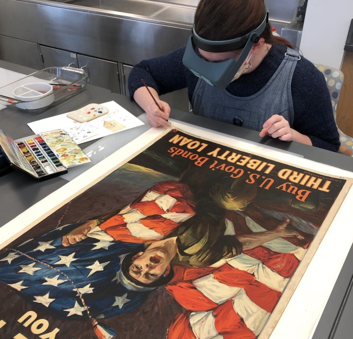 Student cleaning a poster